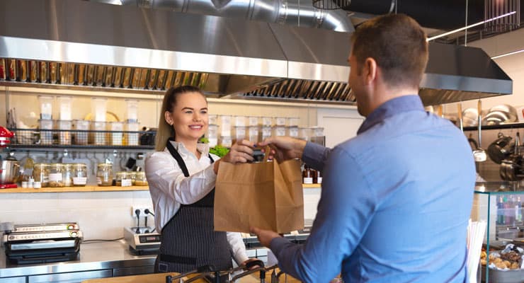 Cliente recibe bolsa de comida en mostrador