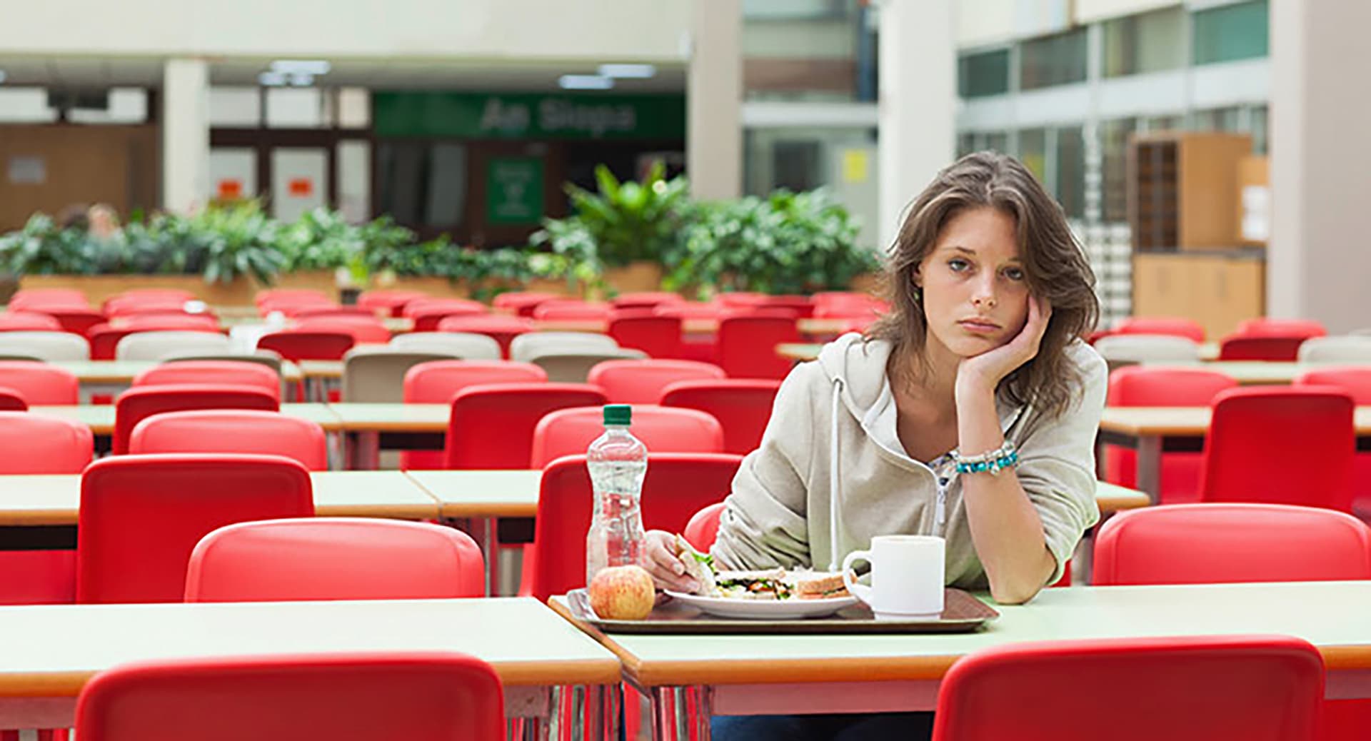 Teenager sitting at a table in a cafeteria