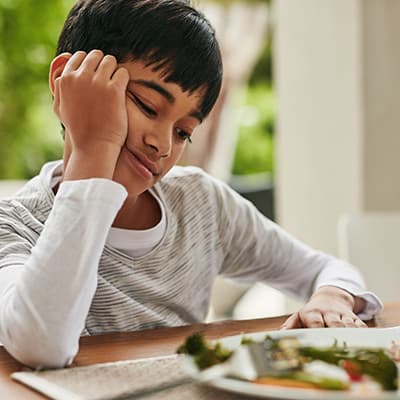 Étudiant avec une assiette pleine de nourriture sur la table devant lui