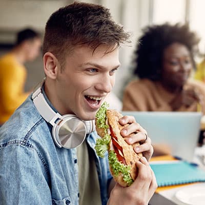 Jugendlicher beisst gleich in belegtes Brötchen