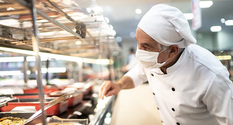 Chef-kok met gezichtsmasker in de keuken